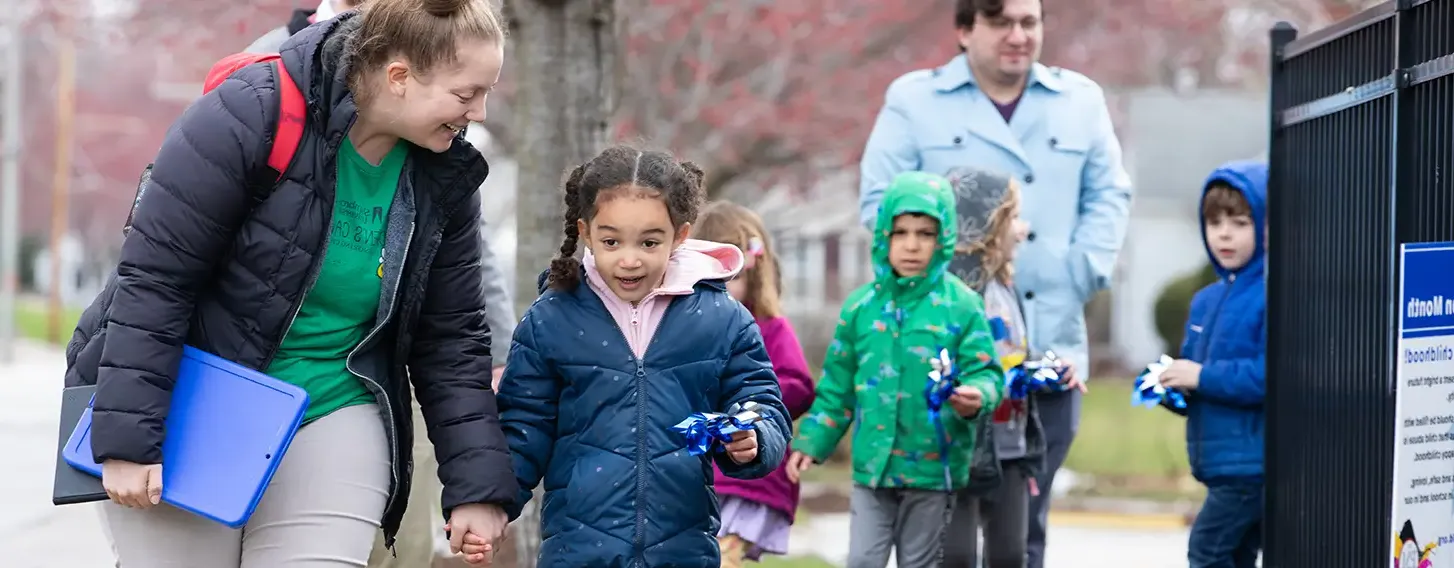 A woman and elementary student walking down a sidewalk outside their school.